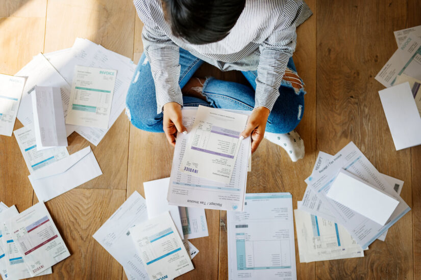 Woman managing debt with many papers on the floor